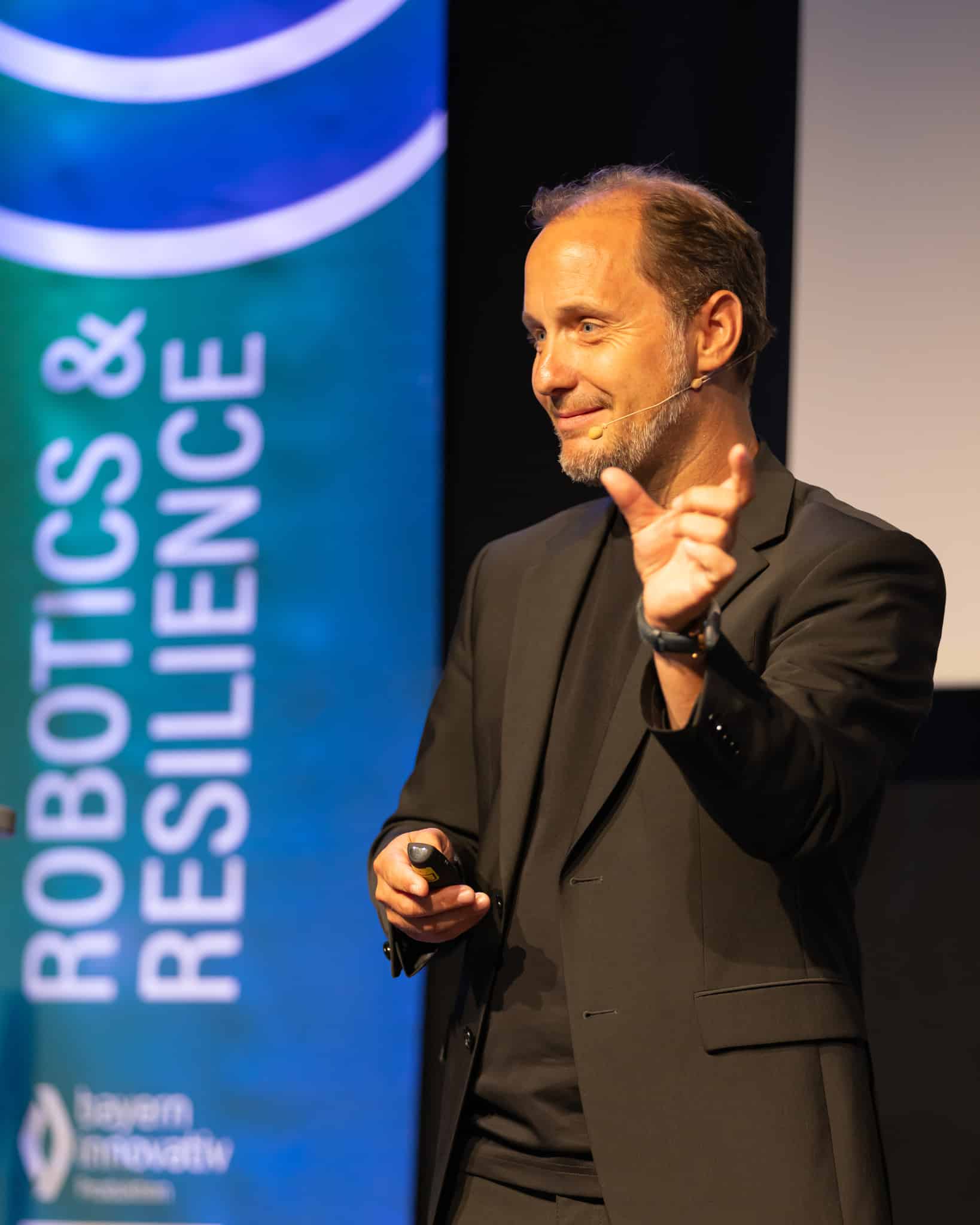 Jürgen Menhart lächelnd im Kontakt mit dem Publikum während seiner Keynote